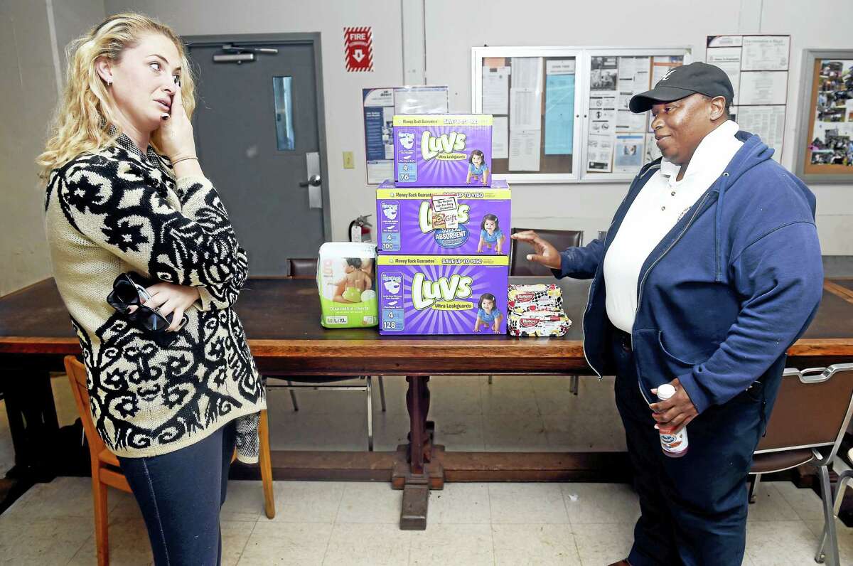 Kelly Soter, left, of Milford, wipes away a tear as she is presented with diapers and a ShopRite Supermarket gift card by Honda Smith at the New Haven Public Works Department in New Haven on 10/14/2016. Smith spearheaded this Act of Kindness with the help of her fellow Public Works Department employees who donated money for the effort.