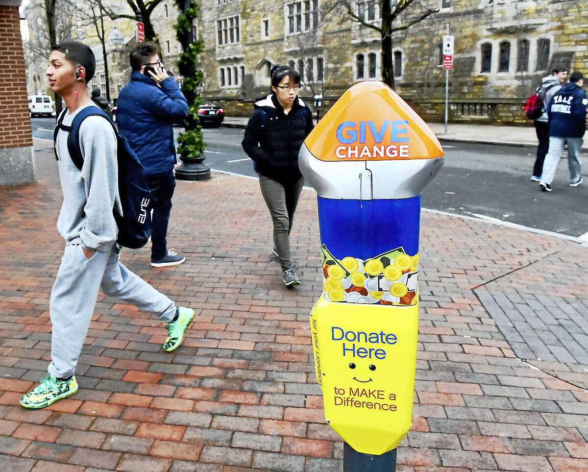 Pedestrians walk by a special parking meter Monday on York Street, designed for donating money to address panhandling and homelessness in New Haven.