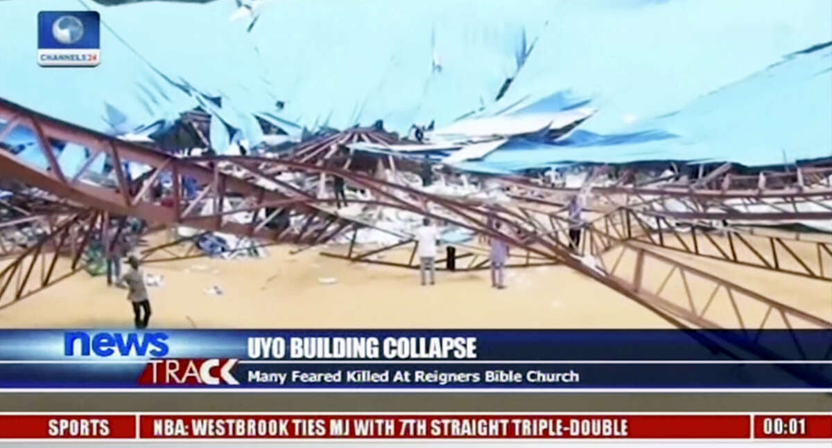In this image taken from video, people stand at the scene after the roof of The Reigners Bible Church International collapsed onto worshippers in Uyo, southern Nigeria on Dec. 10, 2016 killing dozens, an official said.
