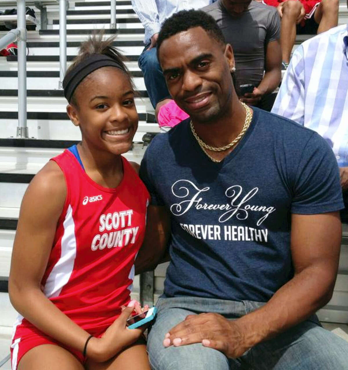 In this photo, Trinity Gay, a seventh-grader racing for her Scott County High School team, poses for a photo with her father Tyson Gay.