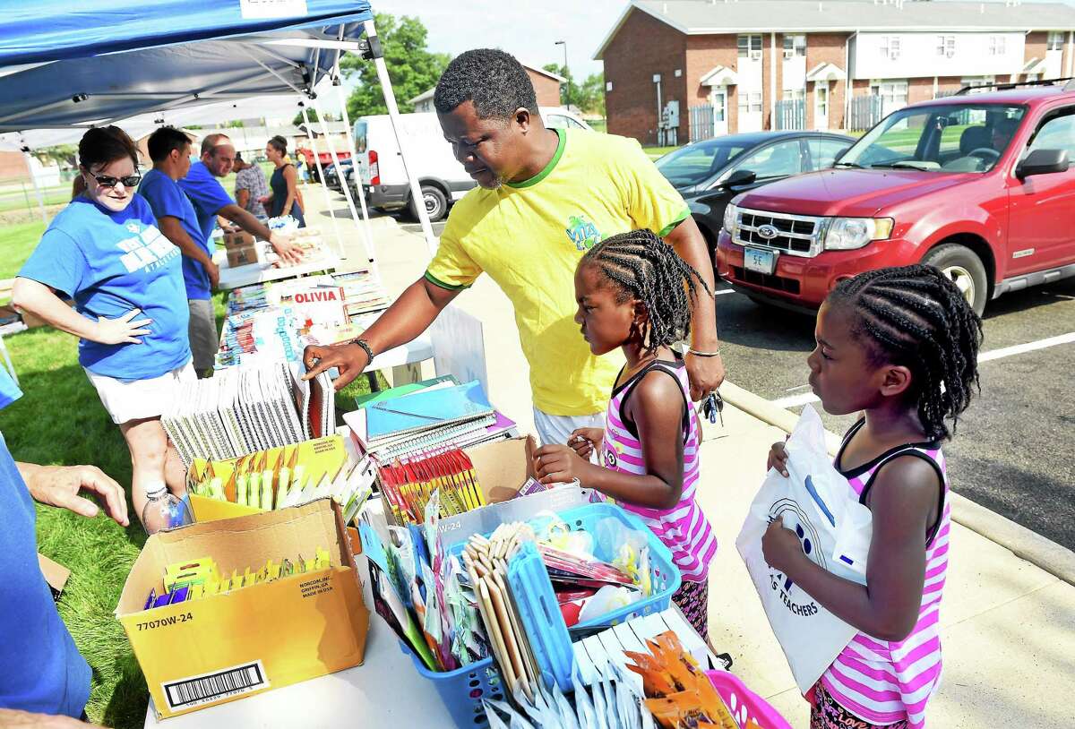 From left, Reuben Walters picks out school supplies with his twin daughters, Reunell and Reunick, 5, at Meadow Landing Apartments in West Haven in 2015.