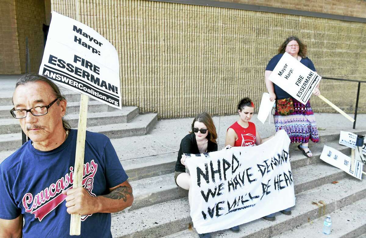 Norman Clement, left, of New Haven protests against New Haven Police Chief Dean Esserman in front of the New Haven Police Department Tuesday.