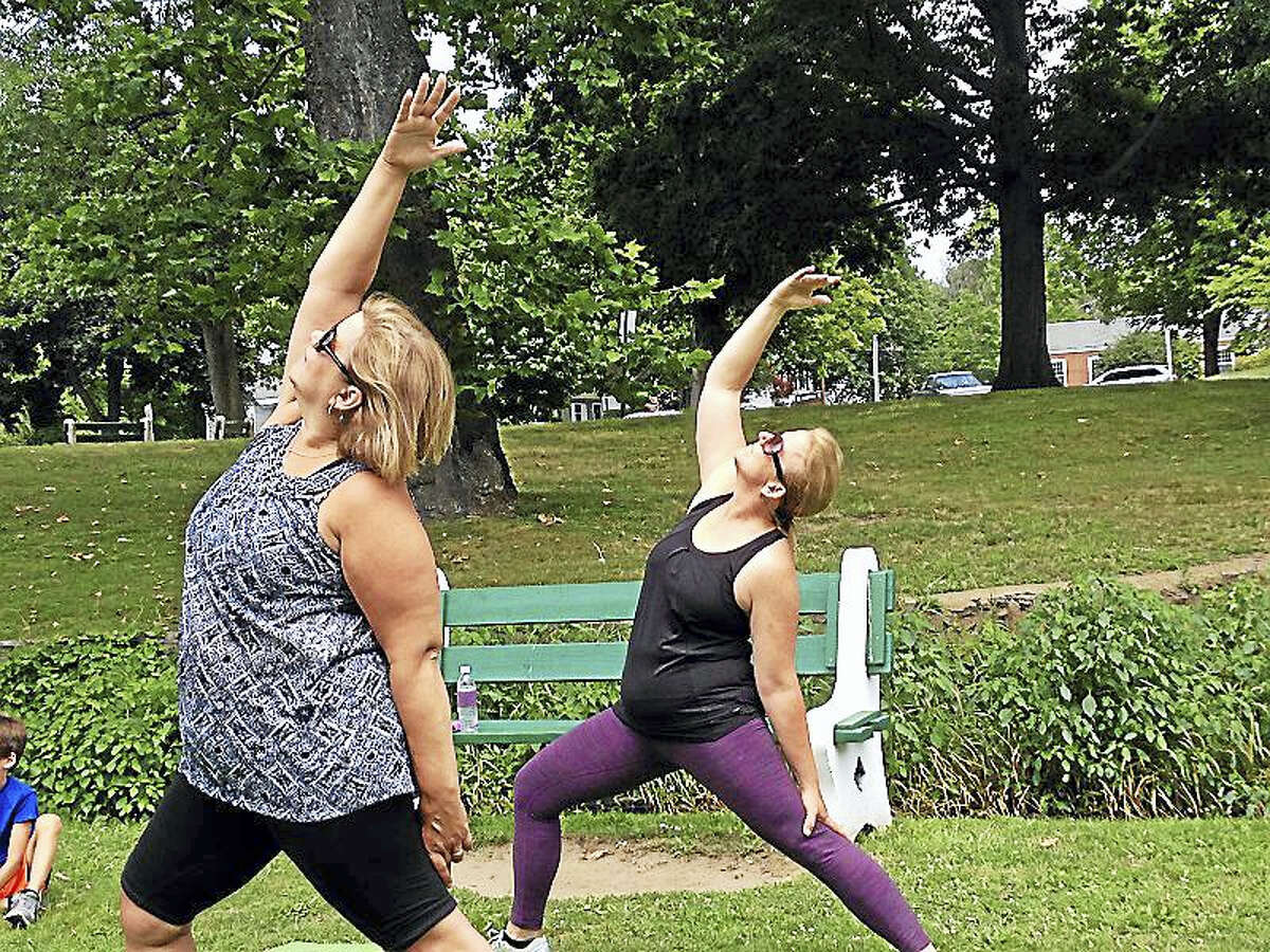 Milford Public School teachers Dawn Bettencourt, left and Tammy Jorgensen, right, love to do yoga and so they decided to try WalkAbout Yoga, whose owner gave a demonstration and class at a recent session of “River Street Wednesdays,” a program of the city and Milford Arts Council.