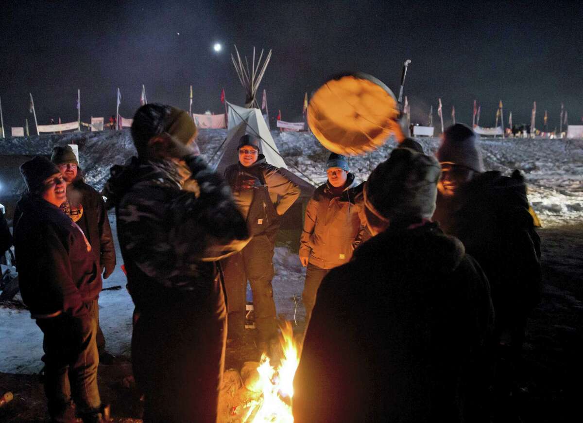 Campers gather around a fire to sing and drum traditional Native American social songs at the Oceti Sakowin camp where people have gathered to protest the Dakota Access oil pipeline in Cannon Ball, N.D. on Sunday, Dec. 4, 2016. U.S. Army Corps of Engineers spokeswoman Moria Kelley said in a news release Sunday that the administration will not allow the four-state, $3.8 billion pipeline to be built under Lake Oahe, a Missouri River reservoir where construction had been on hold.