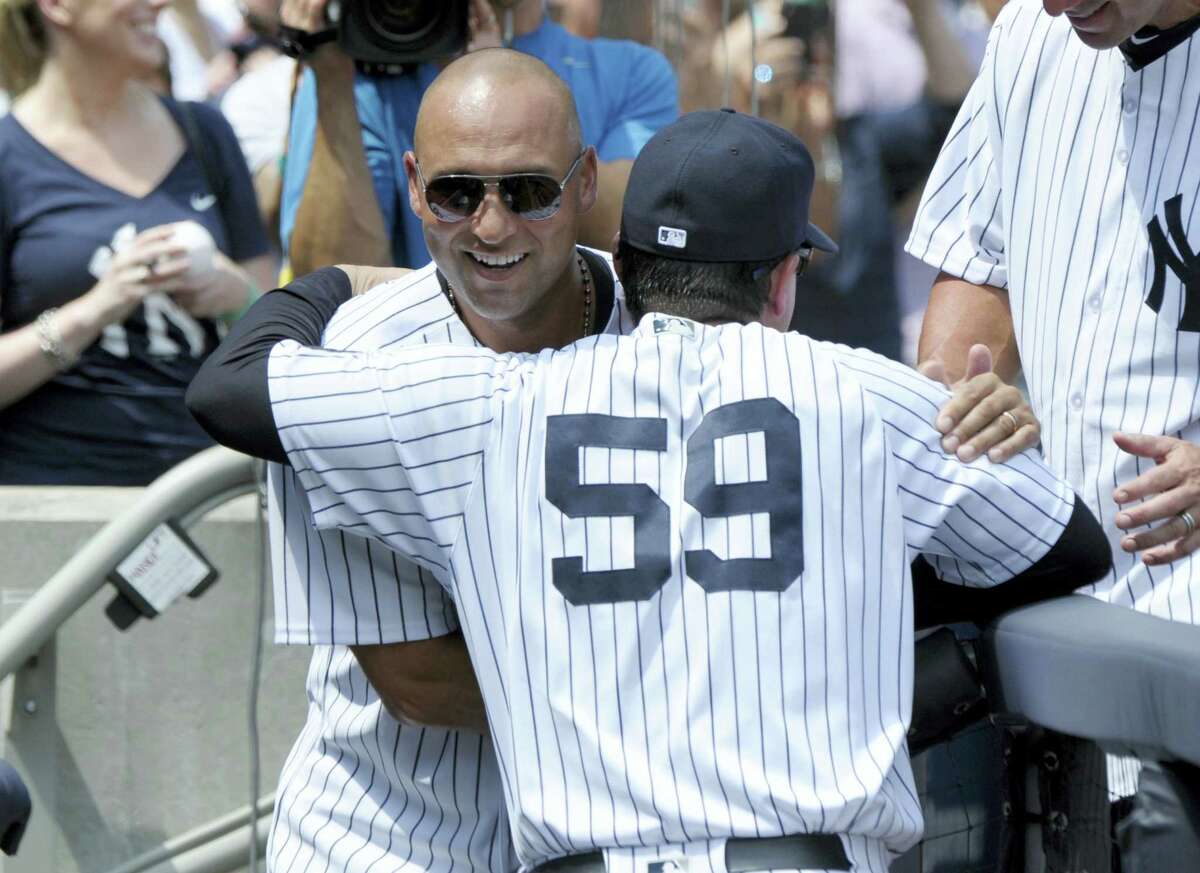 Former Yankees shortstop Derek Jeter hugs bench coach Rob Thompson before a Saturday’s game at Yankee Stadium in New York. The 1996 Yankees team was honored before the game.