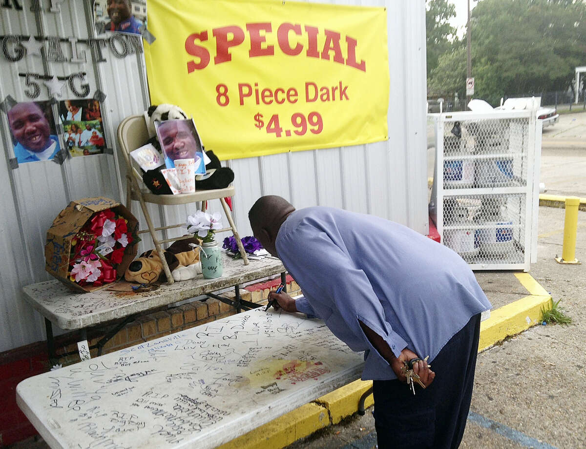 Arthur Baines signs “RIP Big Dogg” on a folding table that Alton Sterling used to sell homemade music CDs outside the convenience store, Wednesday, July 6, 2016, in Baton Rouge, La. A Louisiana police officer shot and killed Sterling, 37, a black man, during a confrontation outside the store, authorities said, prompting hundreds to protest at the site where the man died.