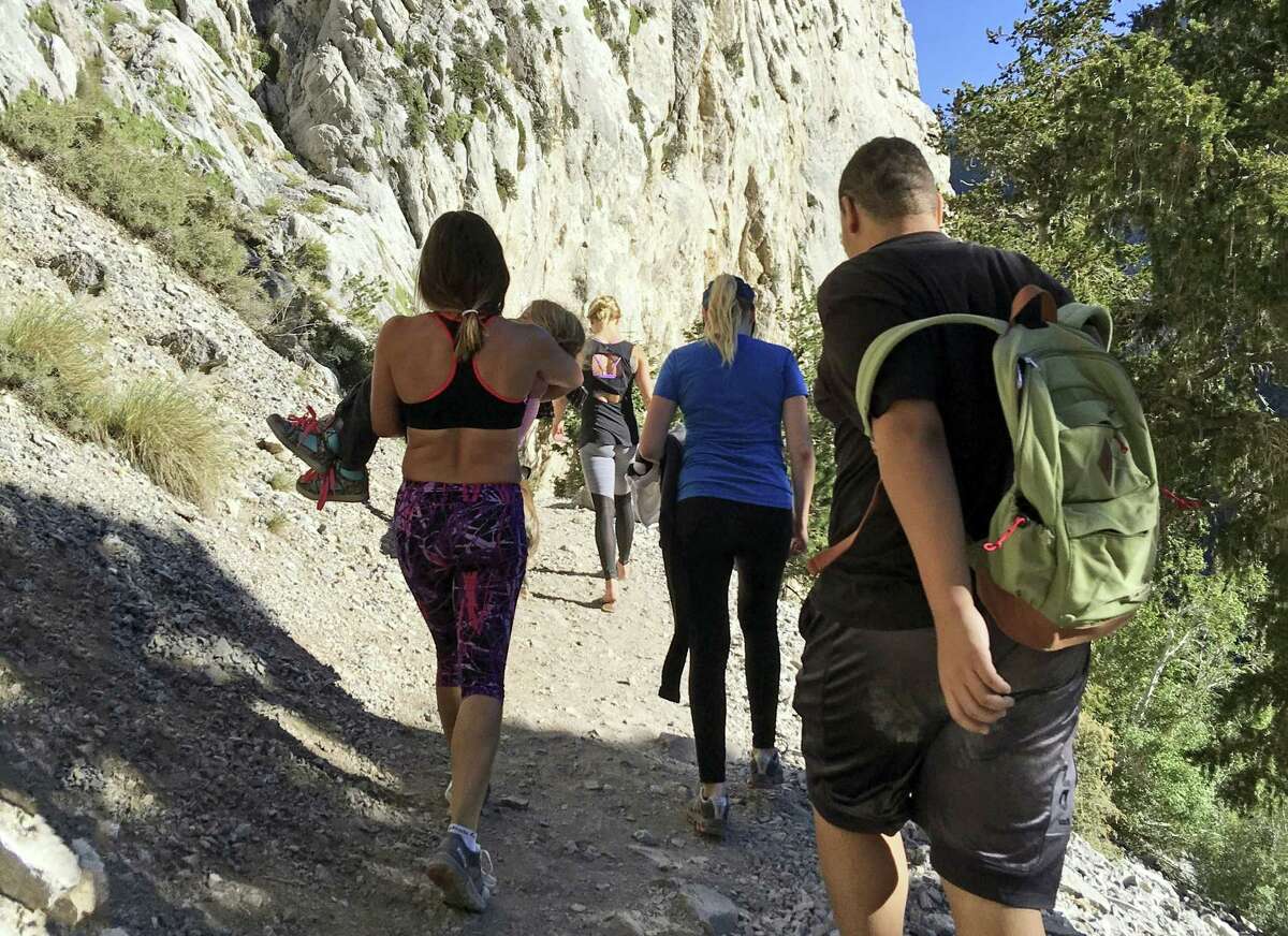 In this Sept. 4, 2016 photo provided by Myra Fukuno, former mixed martial arts Ultimate Fighting Championship women’s bantamweight champion Miesha Tate, left, carries a little girl with a broken arm down Mount Charleston near Las Vegas. Tate says she’s inspired by the tough little girl who broke her arm while hiking near Las Vegas.