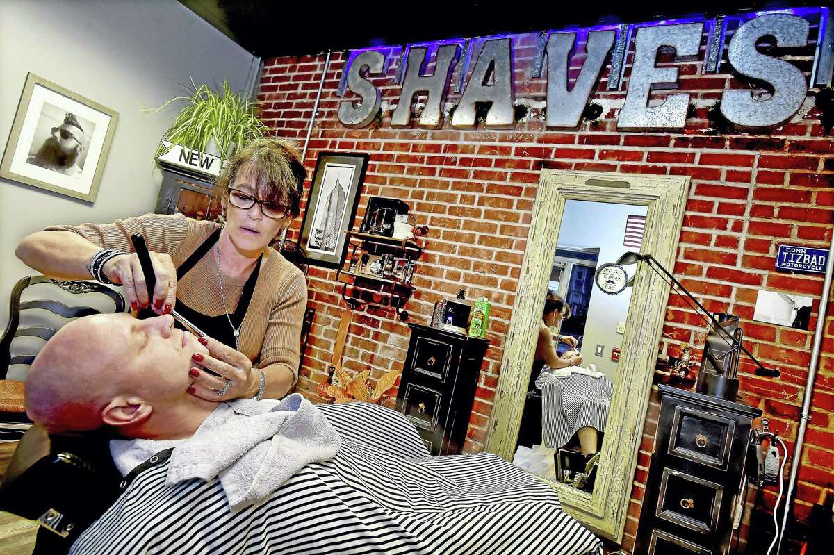 Barber Susan Hushin, owner of BBS Shave Studio at 58 River St. in Milford, uses a straight razor to give Milford resident Bill Parry a wet shave.