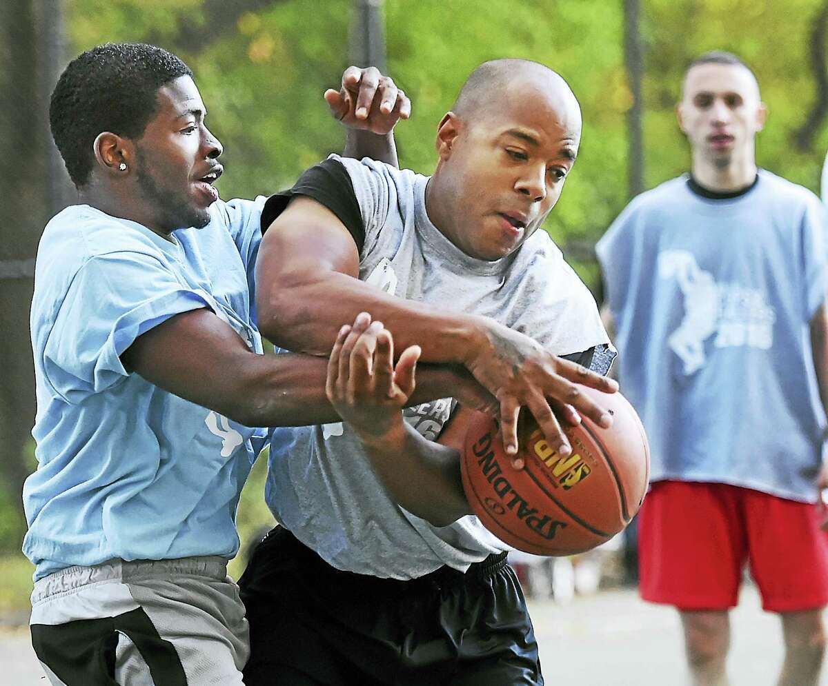 Trevon Gray, left, and Officer John Moore battle for posession as Officer Greg Ammon keeps his eye on the play at the “Cops and Ballers” community basketball tournament Wednesday in New Haven.