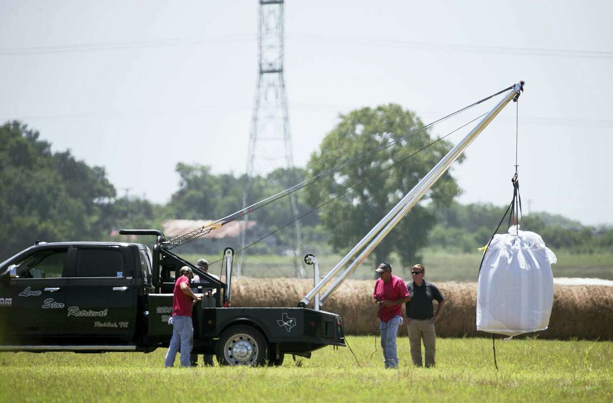 A crew hoists a bag holding the remains of a hot air balloon that crashed Saturday onto a waiting truck at the scene near Lockhart, Texas, Monday, Aug. 1, 2016. Sixteen people were killed in the incident.