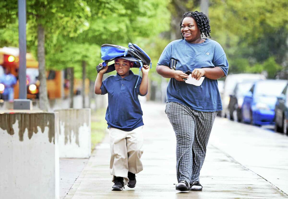 First-grader Christopher Parker, 6, walks into East Rock School with his mother, Dashawna Garner, in New Haven on the first day of school Thursday.
