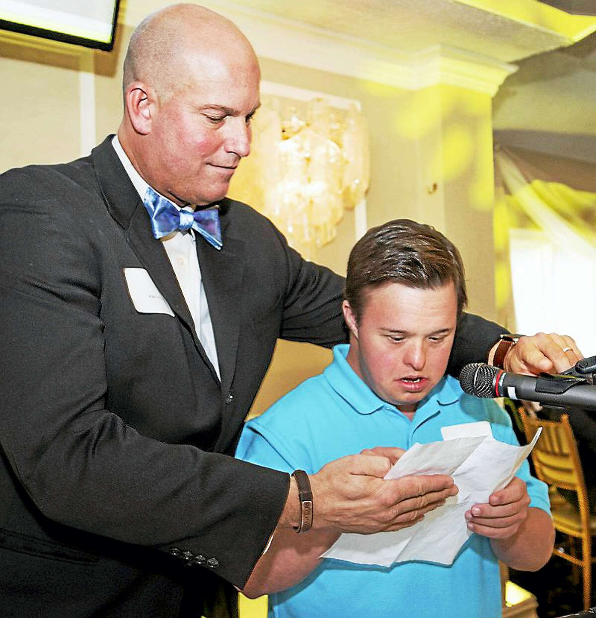 Chapel Haven president Mike Storz helps student Matthew Biles, who spoke at the organization’s annual brunch, where a major capital campaign was formally announced in order to carry out a major expansion and modernization of the campus.