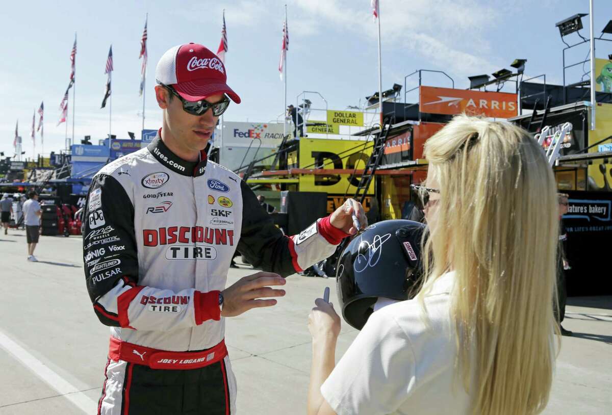 Joey Logano, left, signs an autograph before practice for Sunday’s Coca-Cola 600.