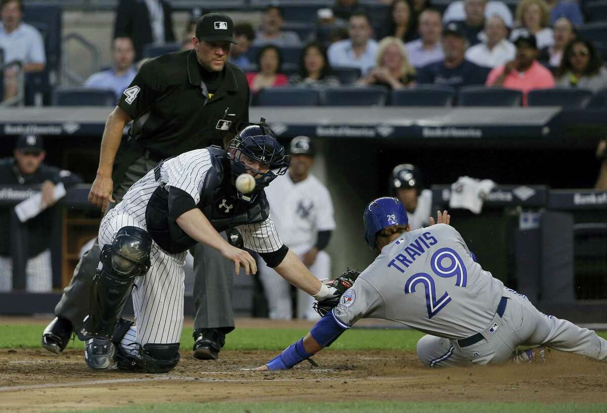 The ball, a double hit to right field by Toronto Blue Jays’ Ryan Goins pops out of New York Yankees catcher Brian McCann’s glove as he attempts to put the tag on Toronto Blue Jays’ Devon Travis (29) during the fourth inning Wednesday in New York. Travis was safe on the play. Kevin Pillar also scored.