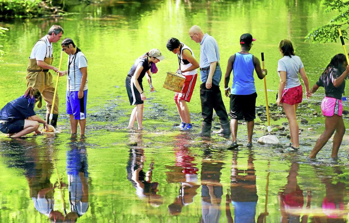 John Triana of the South Central Connecticut Regional Water Authority, second from left, and Larry L. Bingaman, president and CEO of the Regional Water Authority, fourth from right, assist in the search for macroinvertebrates on a field trip to the Mill River in Hamden Wednesday with Environmental Career Summer Camp students. The summer camp is sponsored by the Regional Water Authority and the Common Grounds school in New Haven.