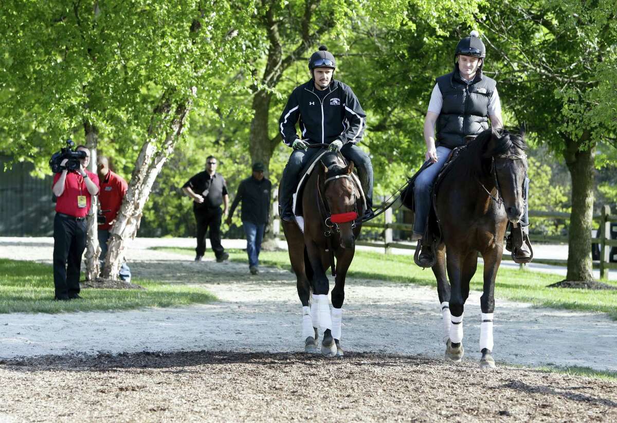 Nyquist, left, ridden by exercise rider Jonny Garcia, walks to the barns with assistant trainer Jack Sisterson at Pimlico Race Course on Friday.