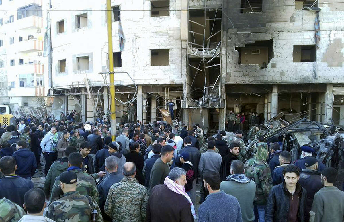 In this photo released by the Syrian official news agency SANA, Syrians gather where three bombs exploded in Sayyda Zeinab, a predominantly Shiite Muslim suburb of the Syrian capital, Syria, Sunday, Jan. 31, 2016. The triple bombing claimed by the extremist Islamic State group killed at least 45 people near the Syrian capital of Damascus on Sunday, overshadowing an already shaky start to what are meant to be indirect Syria peace talks.