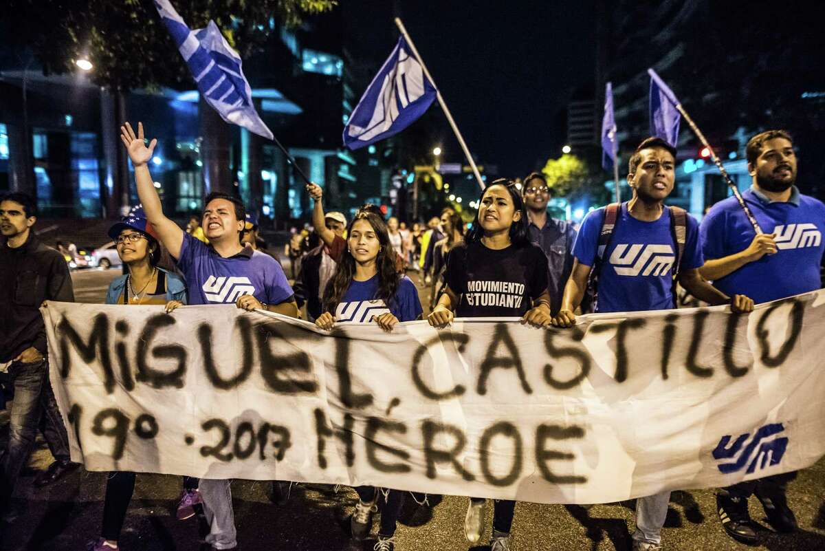Anti-government demonstrators hold a sign reading "Miguel Castillo, Hero" during a vigil, honoring protesters allegedly killed by security forces, in the Chacao district of Caracas, Venezuela, on Thursday, July 13, 2017. In mornings and afternoons,Â protesters pack Chacao's plazas and streets, erecting barricades and throwing stones. After the sun goes down, bars light up. For a select few Venezuelans, the epicenter of unrest is also the best place to escape the country's myriad woes. Photographer: Meridith Kohut/Bloomberg