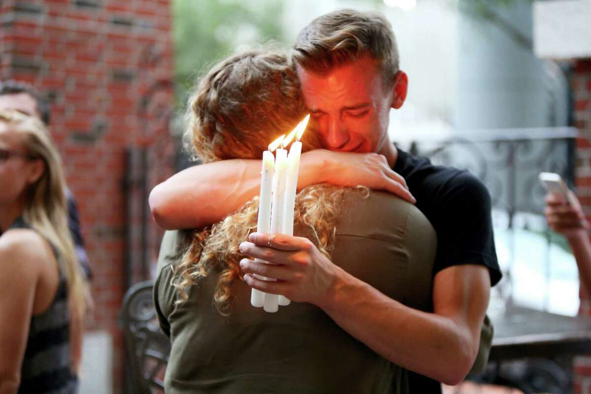 Joshua Lim/Orlando Sentinel via AP Brett Morian, from Daytona Beach, hugs an attendee during the candlelight vigil at Ember in Orlando, Fla., on Sunday.