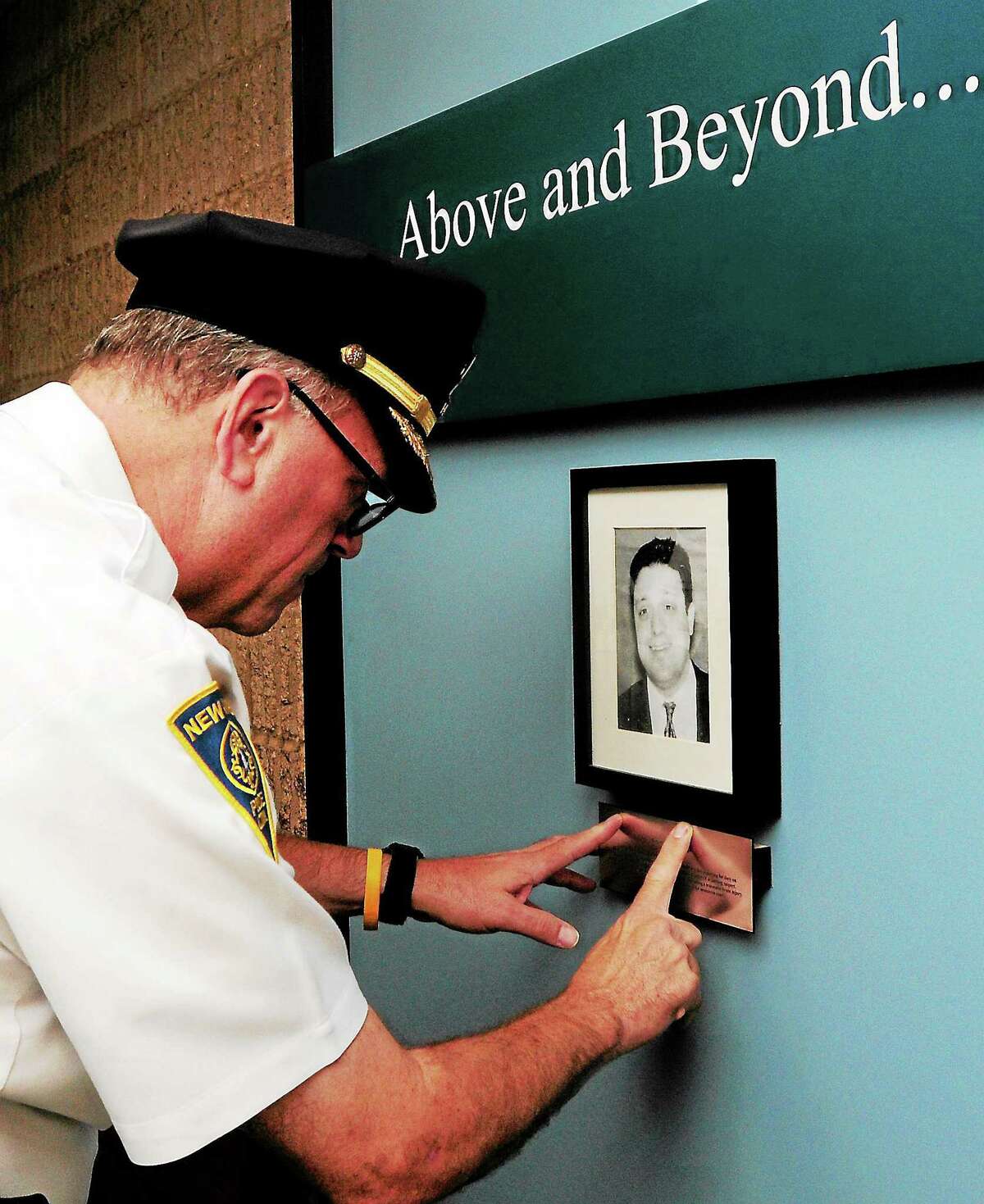 New Haven Police Chief Dean Esserman looks closely at a plaque honoring deceased NHPD Detective Andrew Faggio on a NHPD memorial wall before the start of a ceremony memorializing Faggio at police headquarters in September 2013.