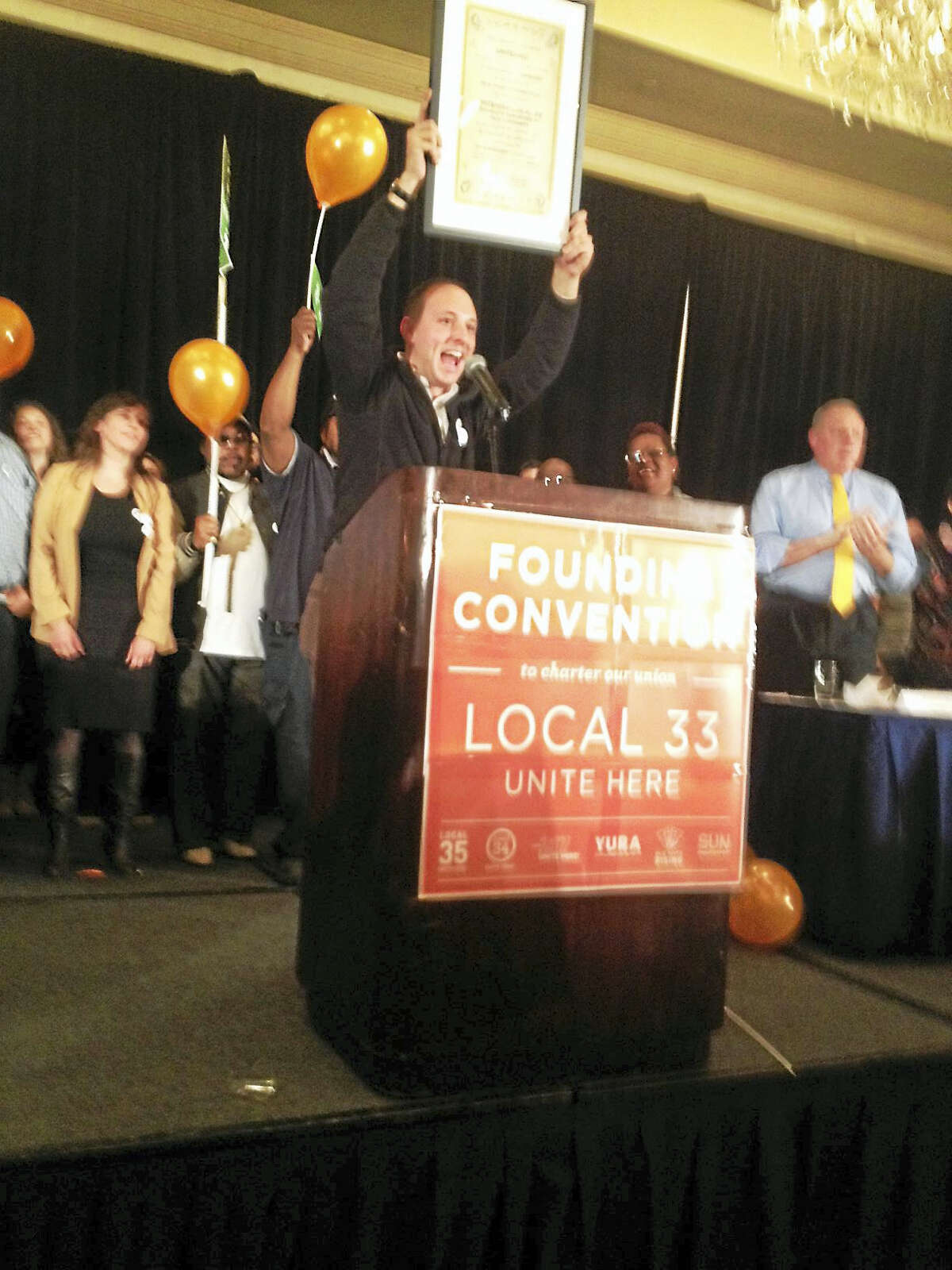 Aaron Greenberg, who headed the organizing committee for Graduate Employees and Students Organization, holds up charter for Local 33 at its founding convention.