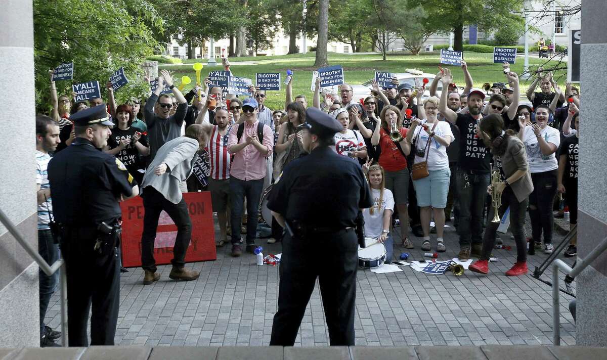Protesters gather outside the North Carolina Museum of History as Gov. Pat McCrory make remarks about House Bill 2 during a government affairs conference in Raleigh, N.C., Wednesday, May 4, 2016. A North Carolina law limiting protections to LGBT people violates federal civil rights laws and can’t be enforced, the U.S. Justice Department said Wednesday, putting the state on notice that it is in danger of being sued and losing hundreds of millions of dollars in federal funding.