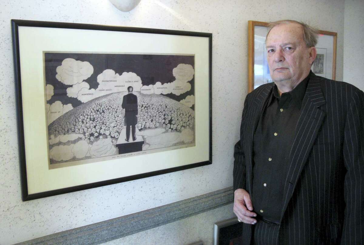 In this April 29, 2016 photo, attorney Bruce Rubenstein, a collector of left-wing political memorabilia, stands in front of a 1920s drawing by political cartoonist Art Young on April 29, 2016 inside his office in Hartford, Conn. Rubenstein is threatening to sue the University of Hartford which plans to sell a political memorabilia collection to which Rubenstein donated hundreds of items.