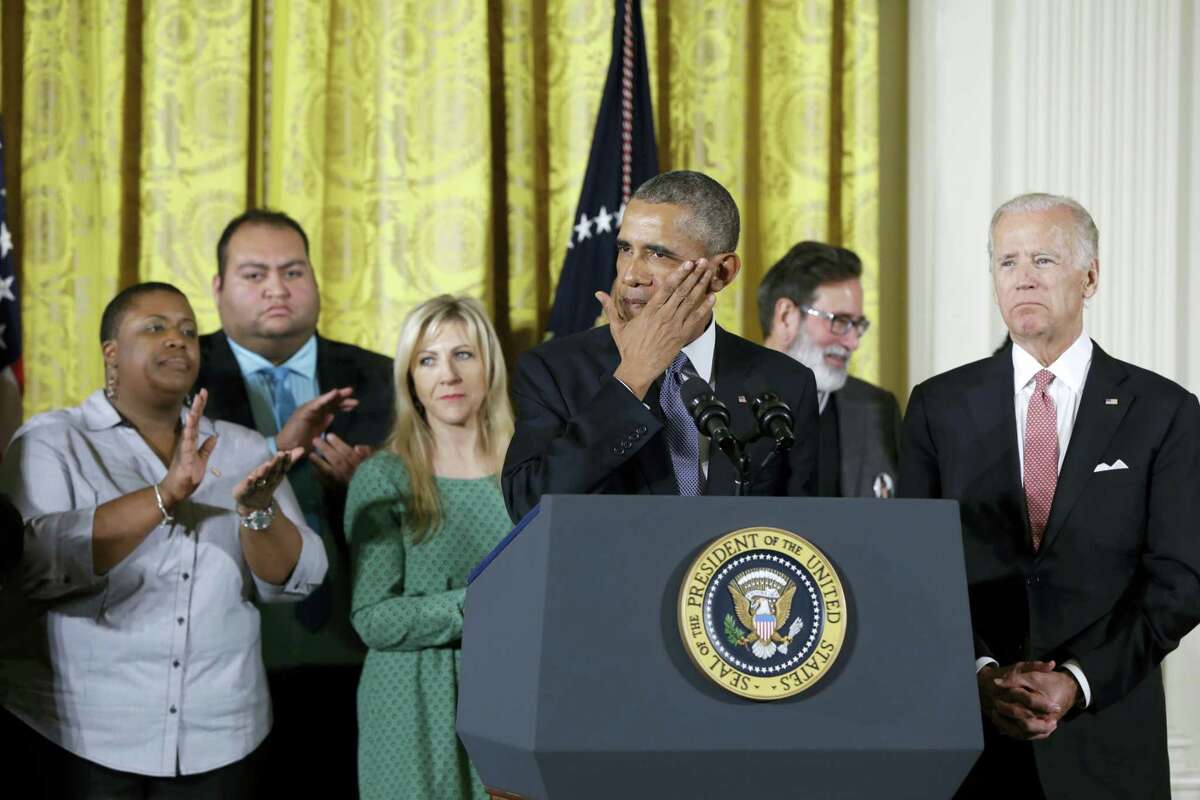 President Barack Obama, joined by Vice President Joe Biden and gun violence victims, wipes a tear from his cheek as speaks in the East Room of the White House in Washington, Tuesday, Jan. 5, 2016, about steps his administration is taking to reduce gun violence. Also on stage are stakeholders, and individuals whose lives have been impacted by the gun violence.