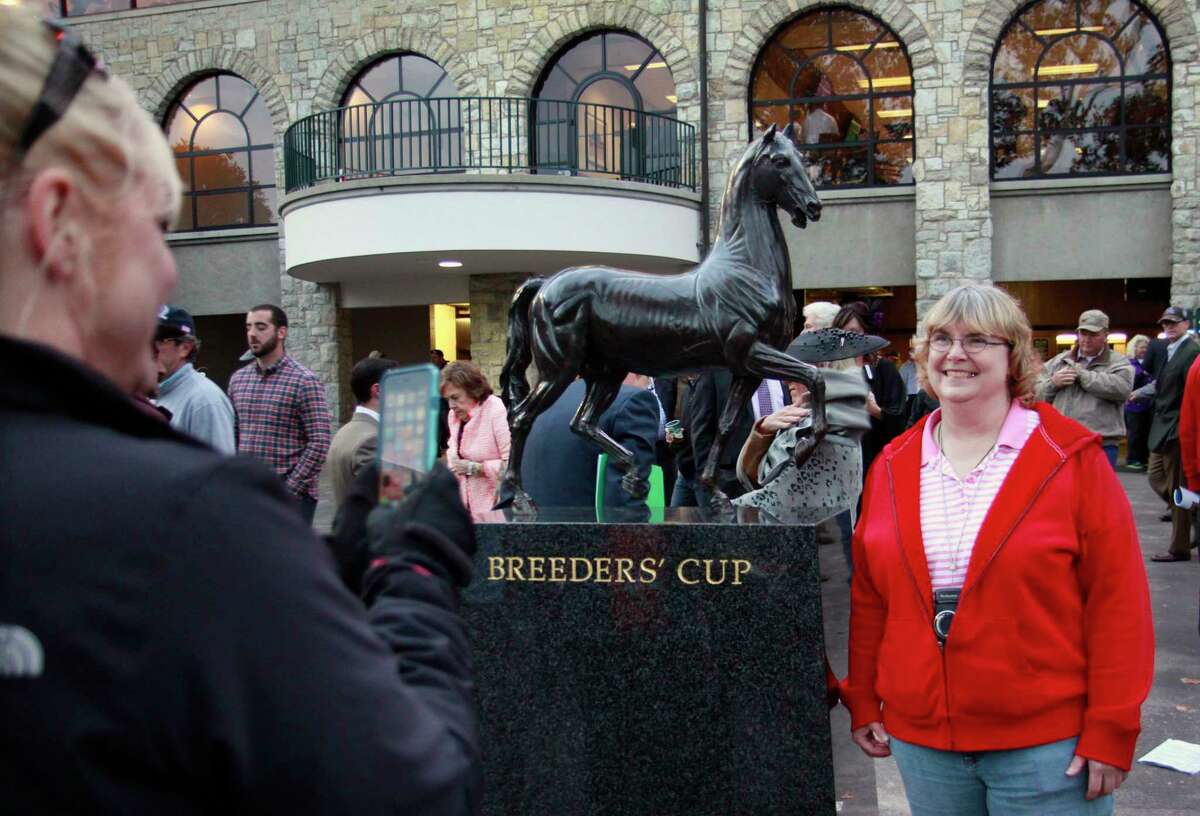 Kim Langston of Daphne, Ala., has her photo taken by a friend by a statue in the grandstand area at Keeneland.