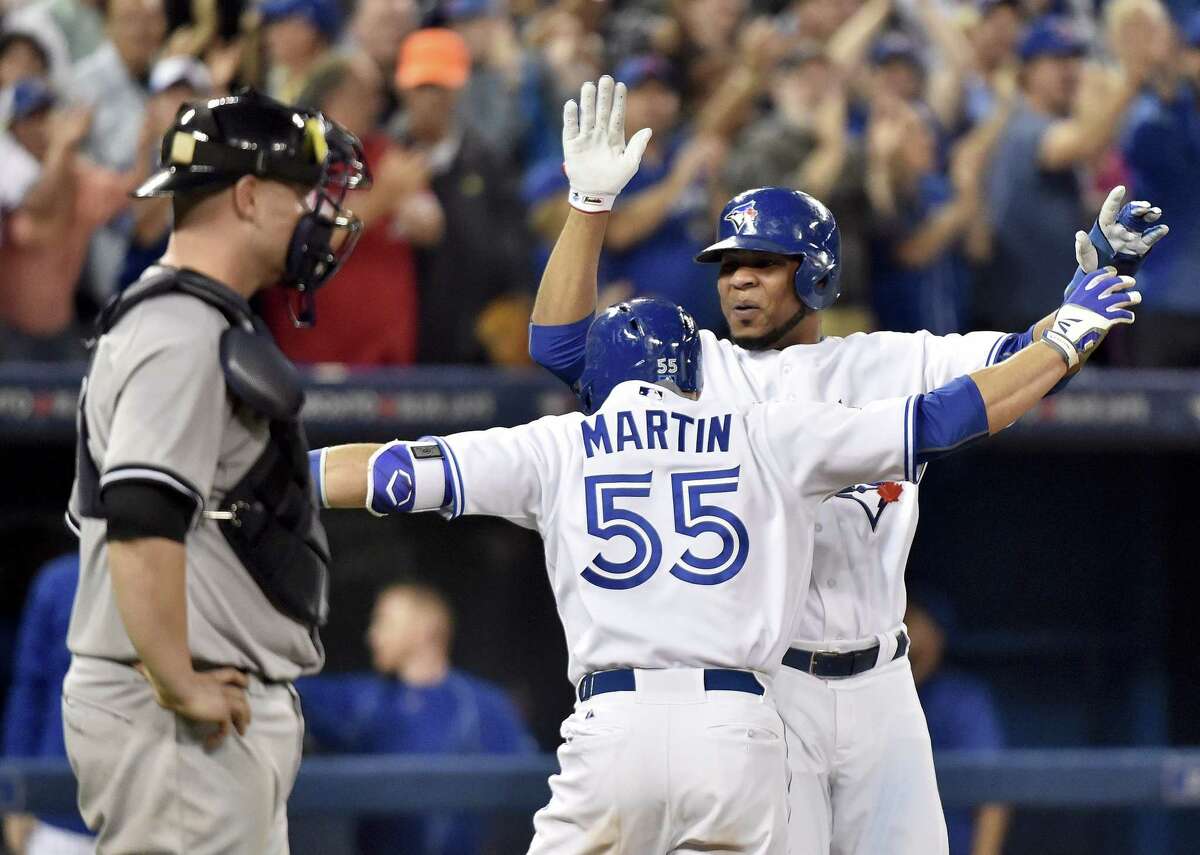 The Blue Jays’ Russell Martin (55) celebrates with Edwin Encarnacion after Martin’s three-run home run as New York Yankees catcher Brain McCann, left, looks on during the Blue Jays’ 4-0 win.