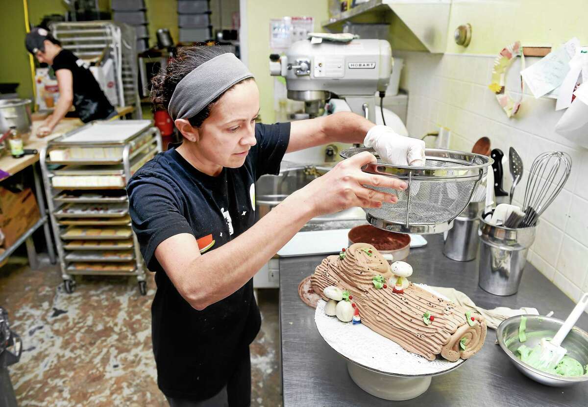 Lesli Flick, owner/baker at Scratch Baking, adds the finishing touches to a Yule log at her bakery in Milford.