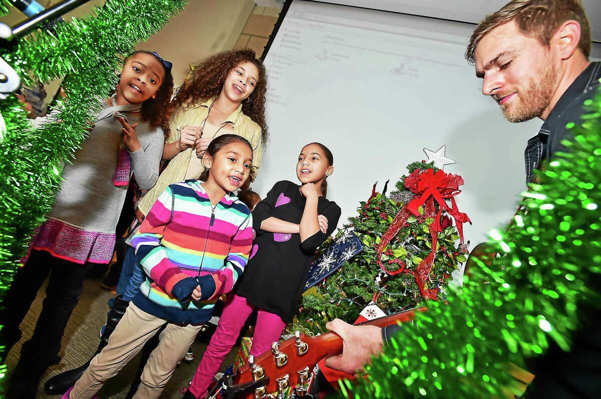 From left, Jada Segui, 10, her 13-year-old sister Yoelys Segui, Nevada Torres, 7, and Karielys Miranda, 10, joined an impromptu caroling session with guitarist Adam Cristoferson of Musical Intervention at a holiday-themed appreciation dinner for Church Street South residents Thursday at Gateway Community College.