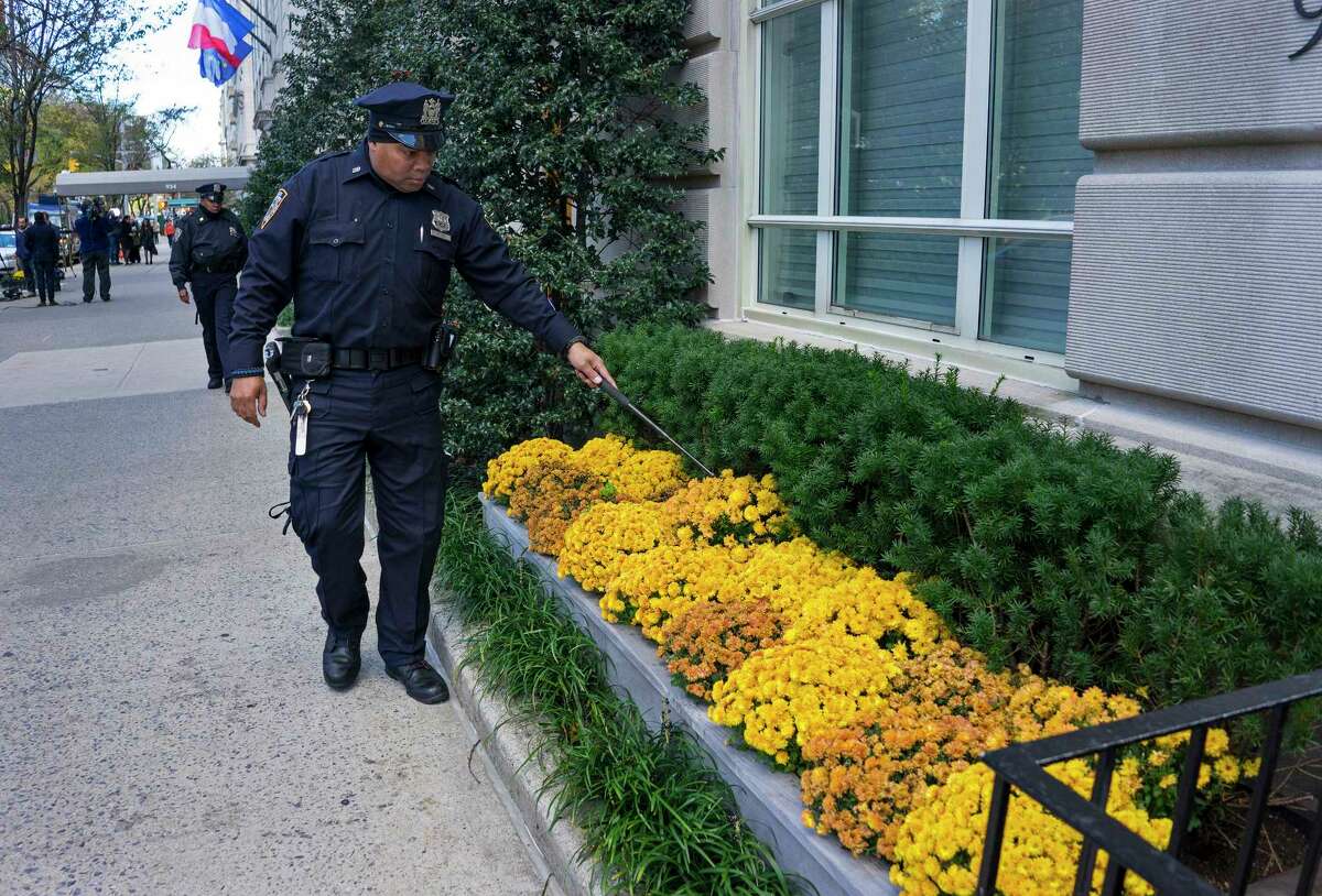 A New York City police officer looks into flower beds at the French consulate in New York, Saturday, Nov. 14, 2015, in the wake of a terrorist attack in Paris Friday. French officials say at least 127 people were killed in shootings and explosions at a theater, restaurant and elsewhere in Paris.