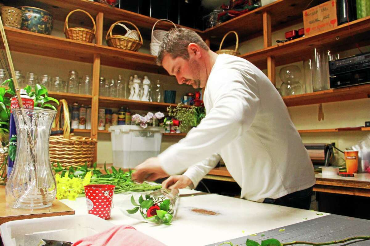 Kyle Curley, of the Flower Girl and Greenhouse Gifts, folds a rose bouquet in this Feb. 14, 2014, file photo in Torringon.