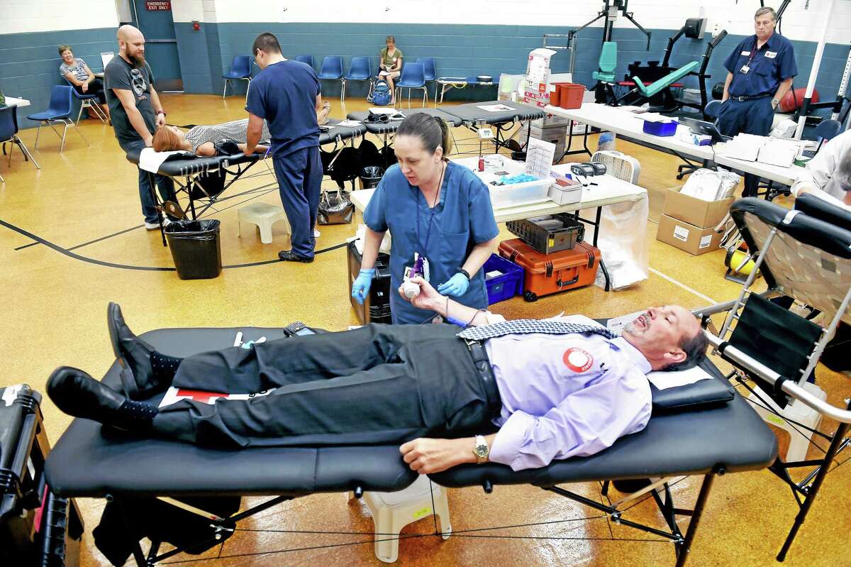 Karla Demers, center, draws blood from Michael Piasecki, CFO of the New Haven Police Department, during a blood drive Tuesday at the department in memory of late Detective Andrew Faggio.