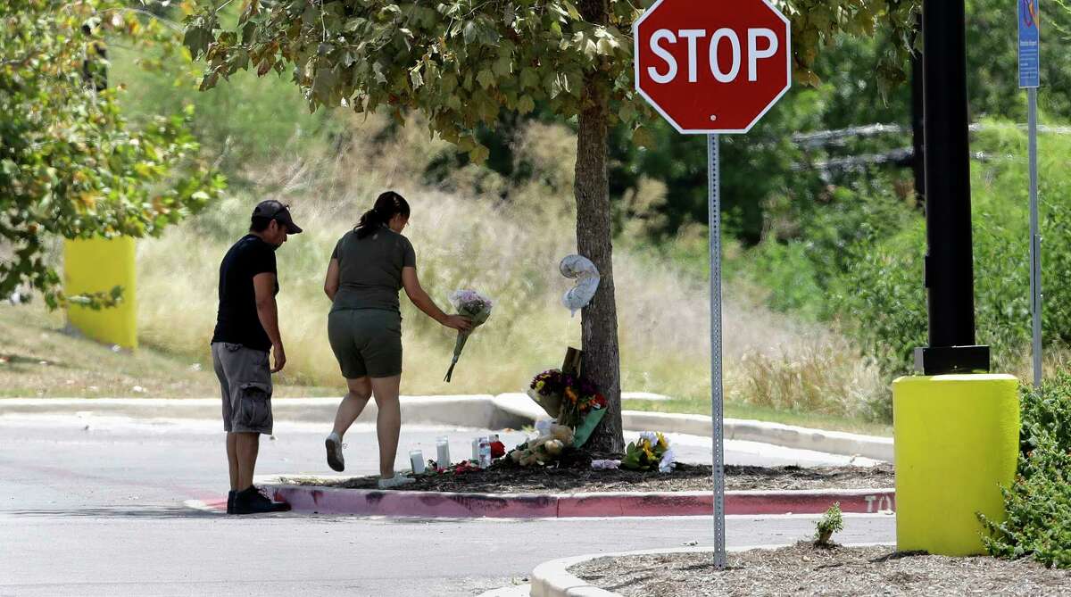 A couple visits a make-shift memorial in the parking lot of a Walmart store near the site where authorities Sunday discovered a tractor-trailer packed with immigrants outside a Walmart in San Antonio.