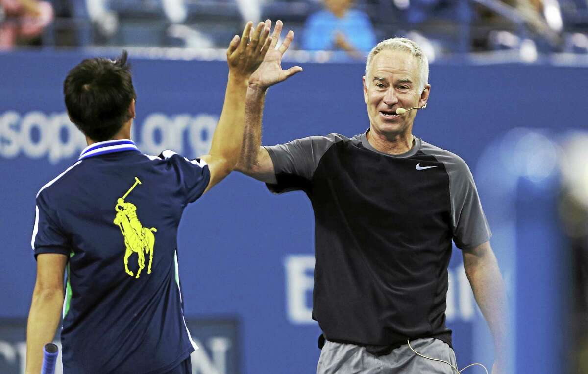 John McEnroe high-fives a ball boy during an exhibition match last September at the U.S. Open in New York.