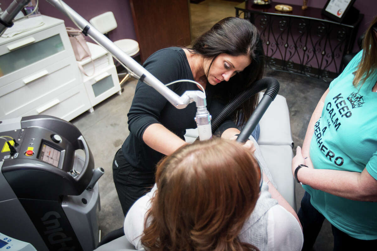 Phoenix Charity founder Tracie Mann performs a tattoo removal procedure on a human trafficking victim Monday at Body Restore Med Spa and Laser Center in The Woodlands.