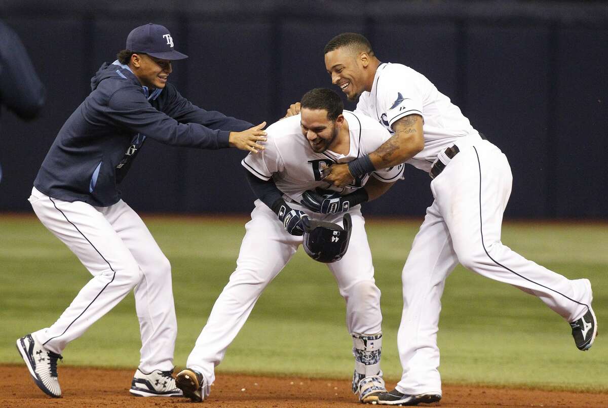 Tampa Bay Rays pitcher Chris Archer, left, and Desmond Jennings, right, jump on Rene Rivera, center, after Rivera’s walk-off single in the ninth inning of Thursday’s game in St. Petersburg, Fla.