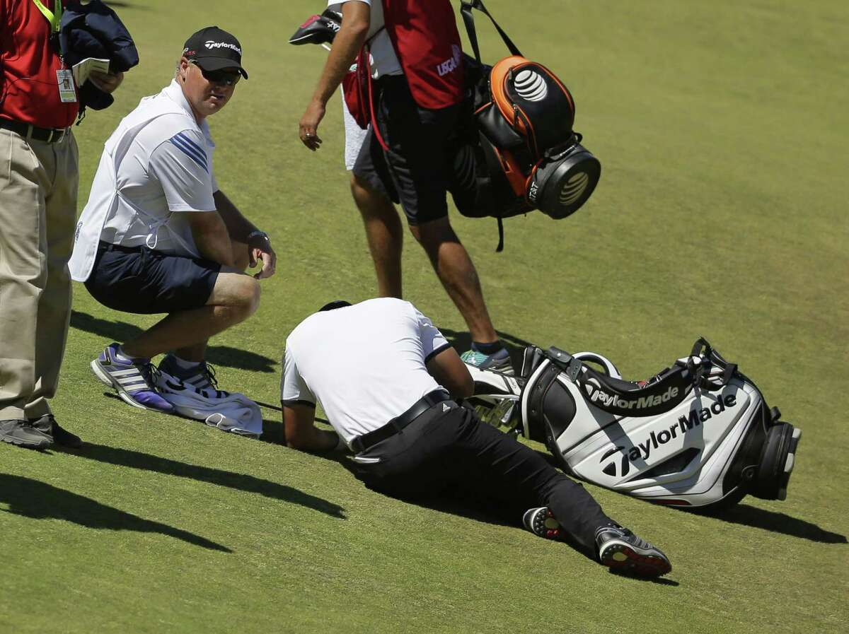 Jason Day lies in the fairway after falling down as his caddie, Colin Swatton, crouches beside him on the ninth hole during the second round of the U.S. Open Friday at Chambers Bay in University Place, Wash.