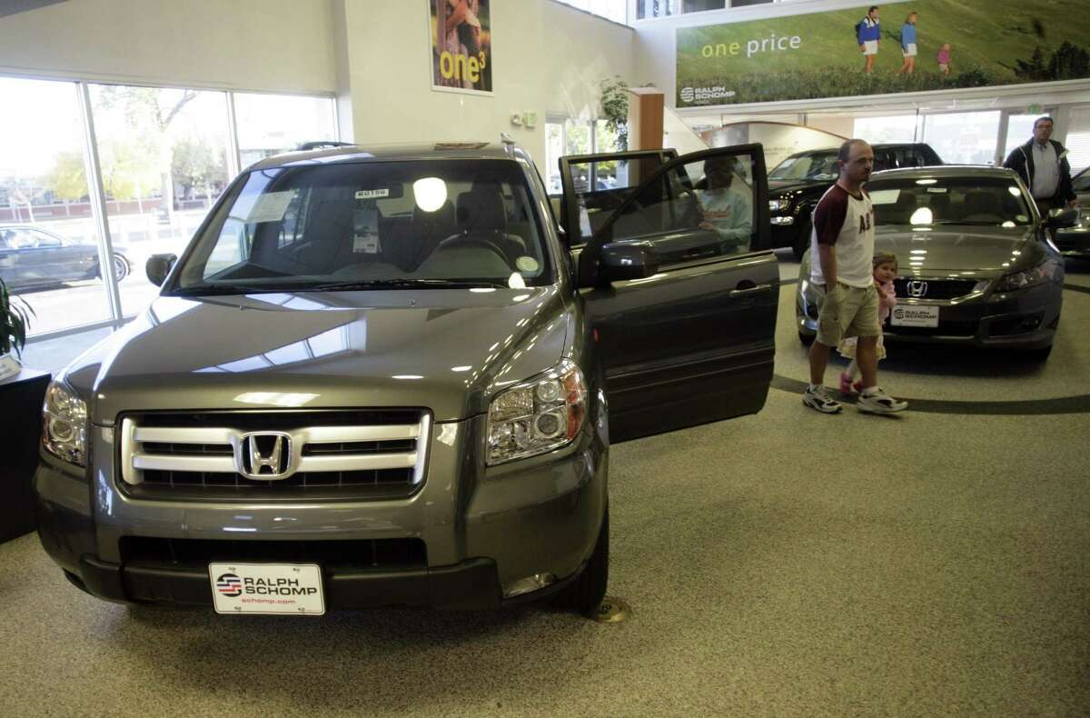 FILE - Buyers look over a 2008 Pilot sports-utility vehicle while a 2008 Accord coupe sits in the background at a Honda dealership in the south Denver suburb of Littleton, Colo., in this Oct. 18, 2007 file photo. Honda is adding nearly 105,000 vehicles to its U.S. recall of driver's side air bag inflators that can explode with too much force. The added vehicles include nearly 89,000 Pilot SUVs from the 2008 model year, as well as about 11,000 Civics from 2004 and another 5,000 Accords from the 2001 model year. (AP Photo/David Zalubowski, FILE)