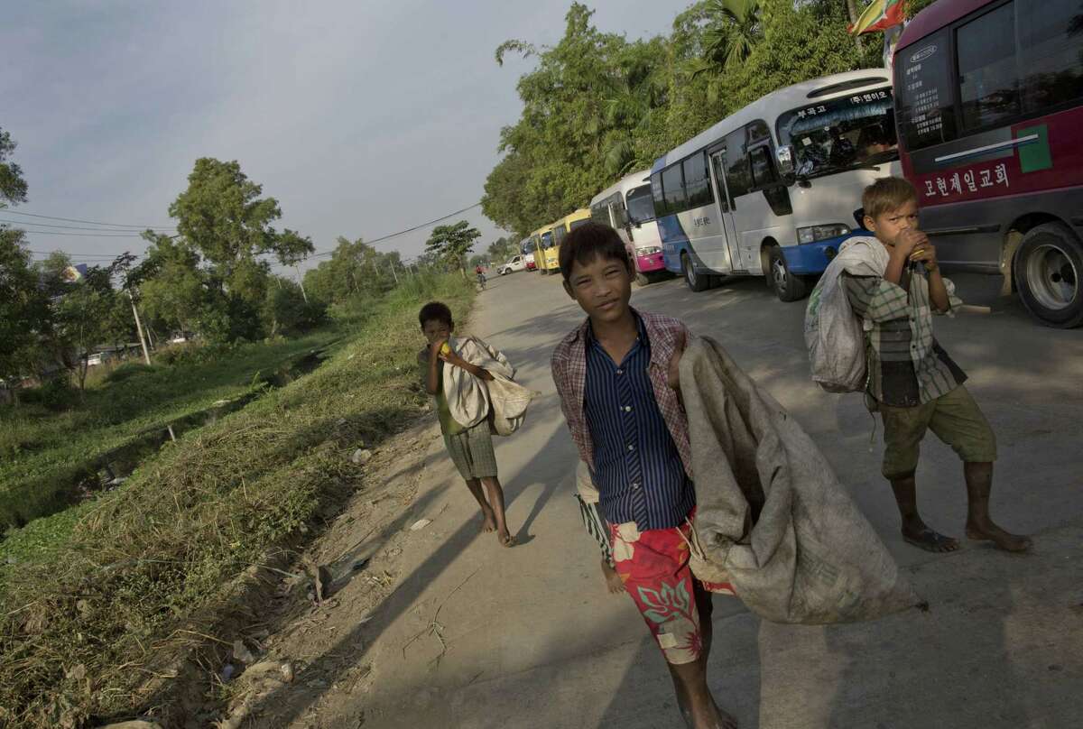 In this Dec. 22, 2014 photo, street children who pick recyclable items from garbage dumps sniff glue as they walk in a street in Hlaing Tharyar, northwest of Yangon, Myanmar. As poor families move from rural areas to the big city in hopes of finding work, many find themselves struggling to get by.