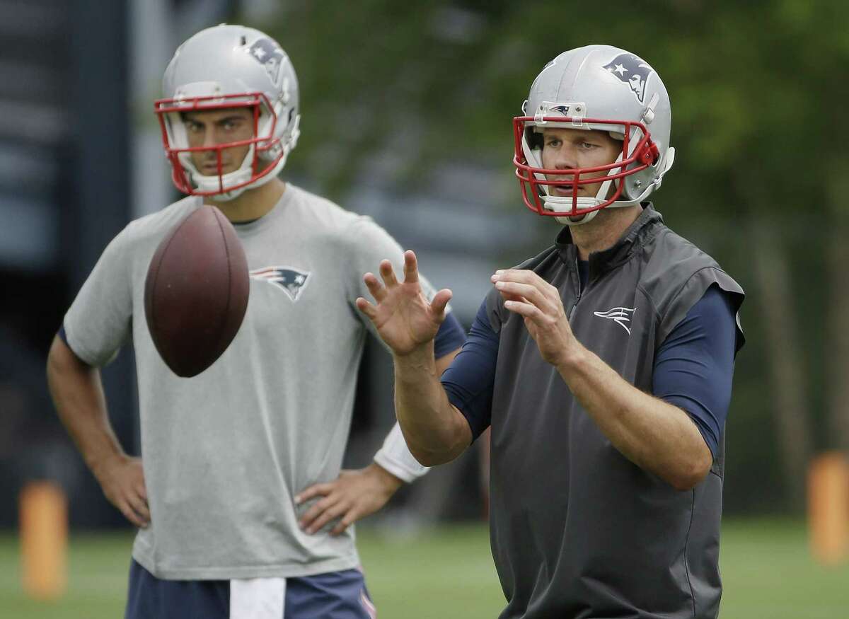New England Patriots quarterback Tom Brady takes a snap as backup quarterback Jimmy Garoppolo looks on during minicamp Wednesday in Foxborough, Mass.