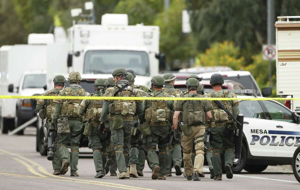 A SWAT team walks down the street near Adams Elementary School searching for a gunman on Wednesday, March 18, 2015 in Mesa, Ariz. A gunman wounded at least four people across multiple locations in the Phoenix suburb. The first shooting happened at a motel, and people were also wounded at a restaurant and nearby apartment complexes. (AP Photo/The Arizona Republic, Rob Schumacher) MARICOPA COUNTY OUT; MAGS OUT; NO SALES