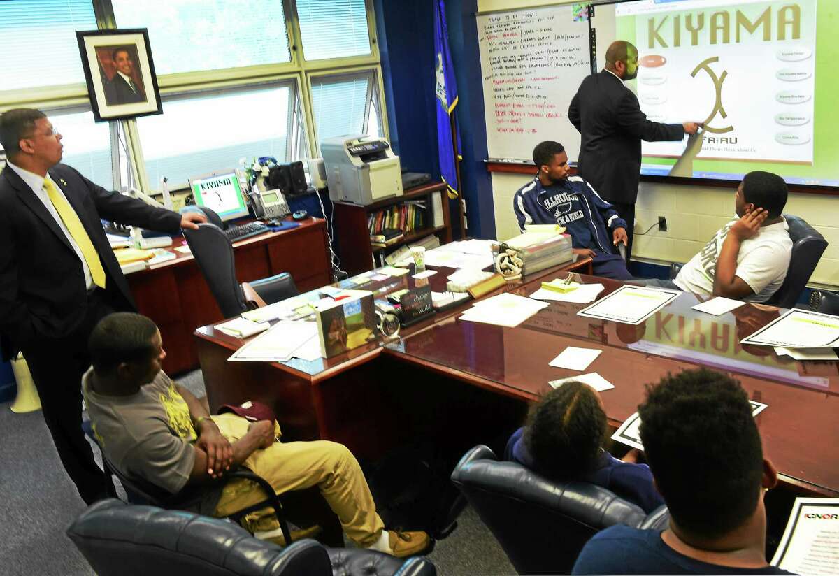 Attorney Michael Jefferson, a human rights activist and founder of The Kiyama Movement, right, explains the Kiyama self-improvement program for young men, particularly young men of color, as he speaks to approximately 20 Hillhouse High School male students at the school Tuesday, May 19, 2015. Hillhouse High School principal Kermit Carolina is at far left.