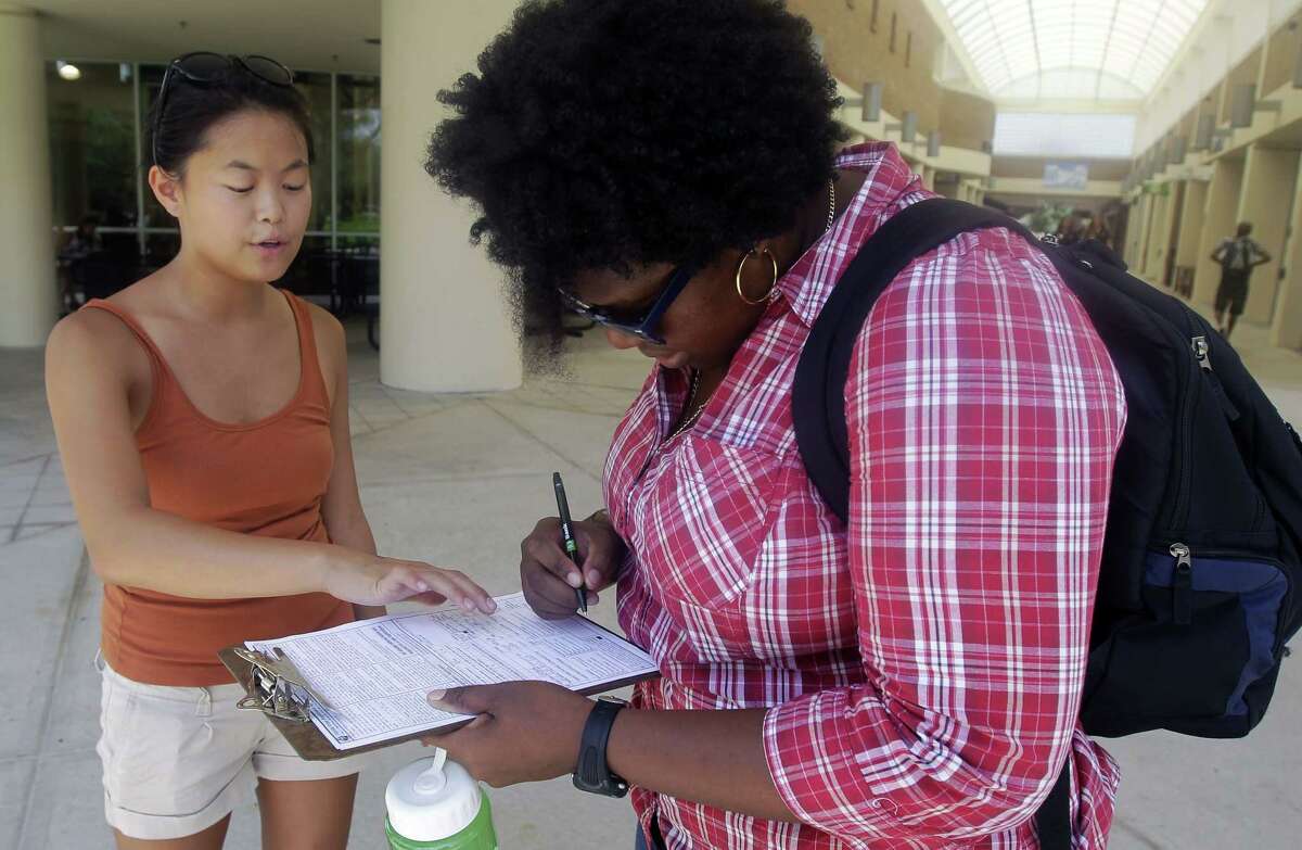 In this July 31, 2012, photo, Aubrey Marks, left, helps a University of Central Florida student to register to vote in Orlando, Fla.