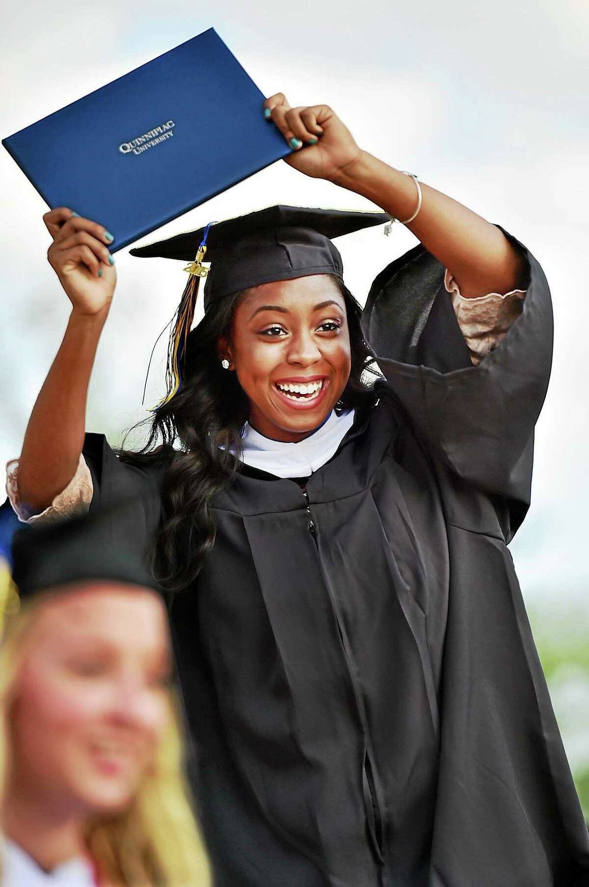 Diamond Lashai Hawkins raises her diploma at Quinnipiac University Sunday.