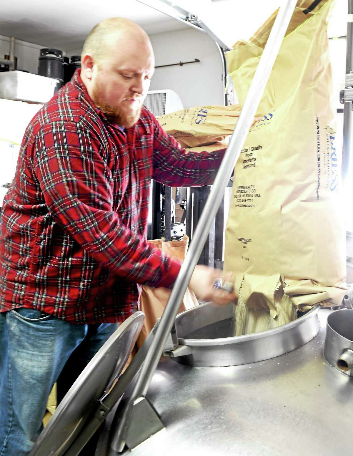 Mike Fawcett, co-founder and Brewmaster at the Thimble Island Brewery in Branford, pours malted barley grain into a Mash Tun filled with hot water during a sugar extraction process that helps make beer. Wednesday, February 11, 2015.