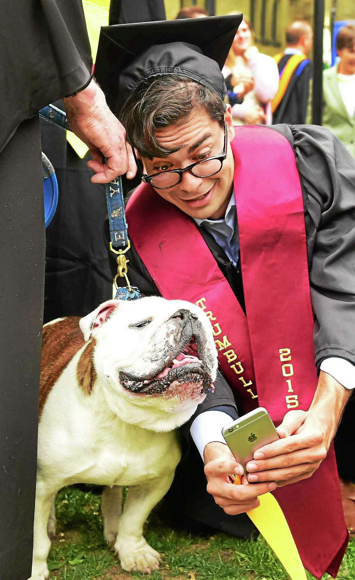 Alexander Saedy of Detroit and Yale’s Trumbull College takes a selfie photo on his iPhone with the Yale bulldog mascot “Sherman” during commencement Monday.