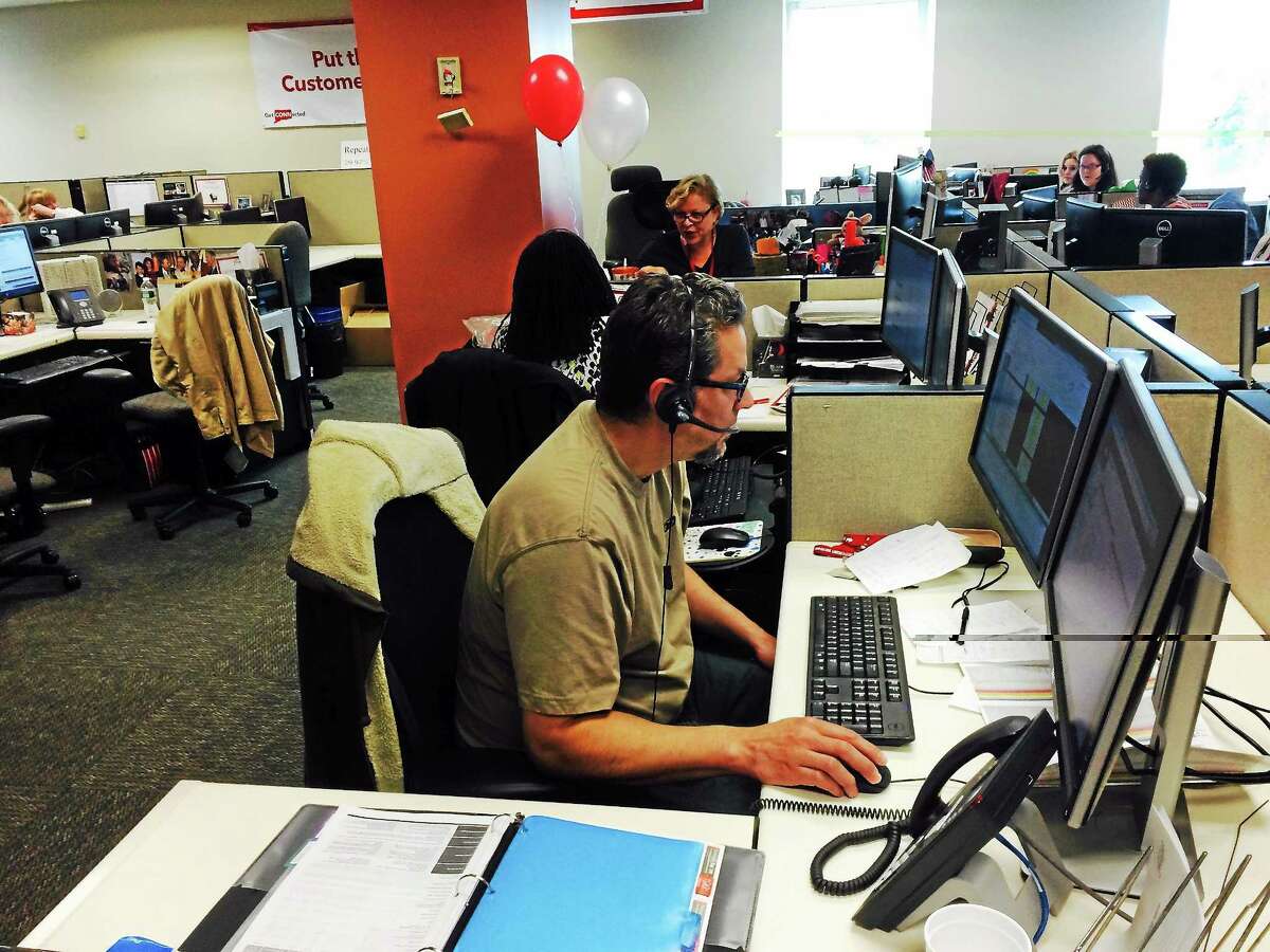 LUTHER TURMELLE — NEW HAVEN REGISTER A Frontier Communications employee helps a customer Monday from his desk at the company’s New Haven call center on Orange Street.